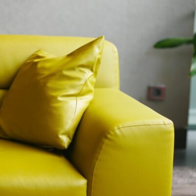 Jasnożółta sofa po renowacji tapicerki skórzanej z dopasowaną poduszką.