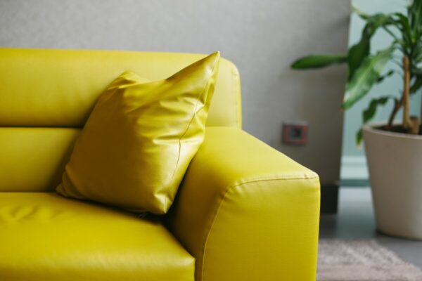 Jasnożółta sofa po renowacji tapicerki skórzanej z dopasowaną poduszką.