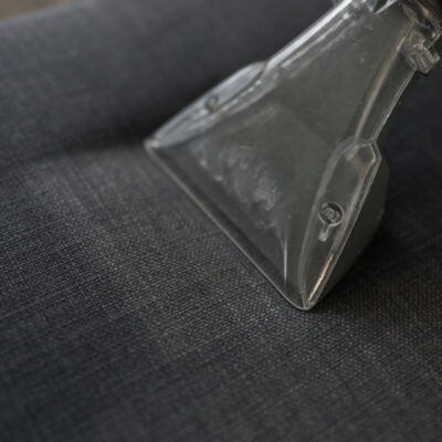 Odkurzacz piorący na ciemnej tkaninie podczas prania tapicerki krzeseł.