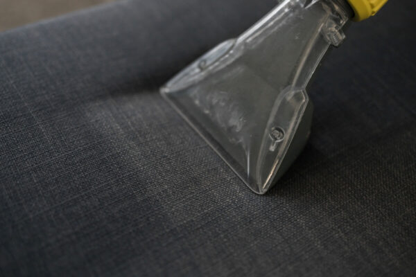 Odkurzacz piorący na ciemnej tkaninie podczas prania tapicerki krzeseł.